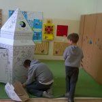 Dzieci bawią się kartonowym domkiem