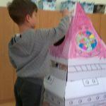 Dziecko bawi się kartonowym domkiem