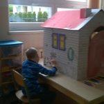 Dziecko bawi się kartonowym domkiem